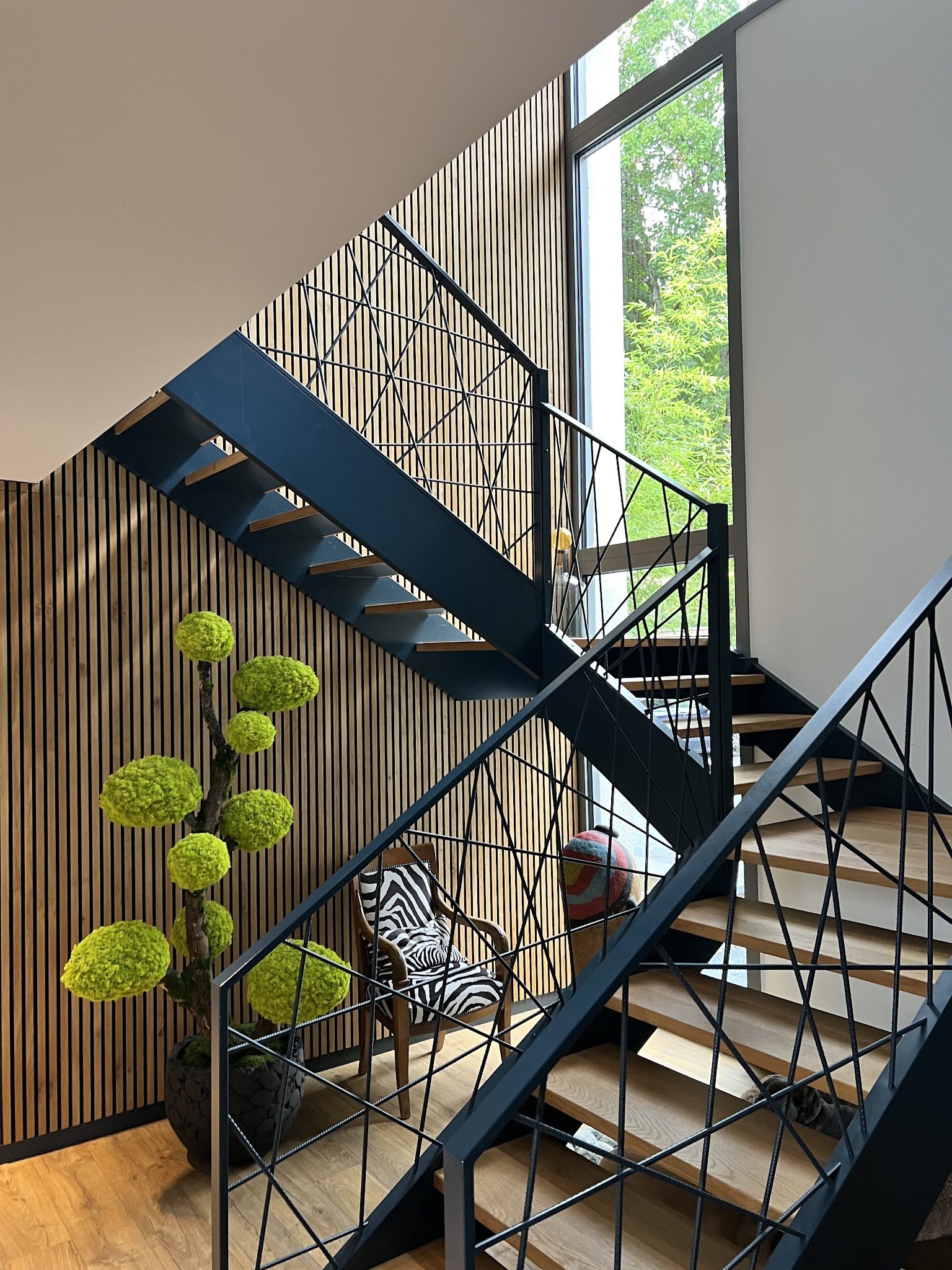 Escalier métallique devant un mur à tasseaux de bois