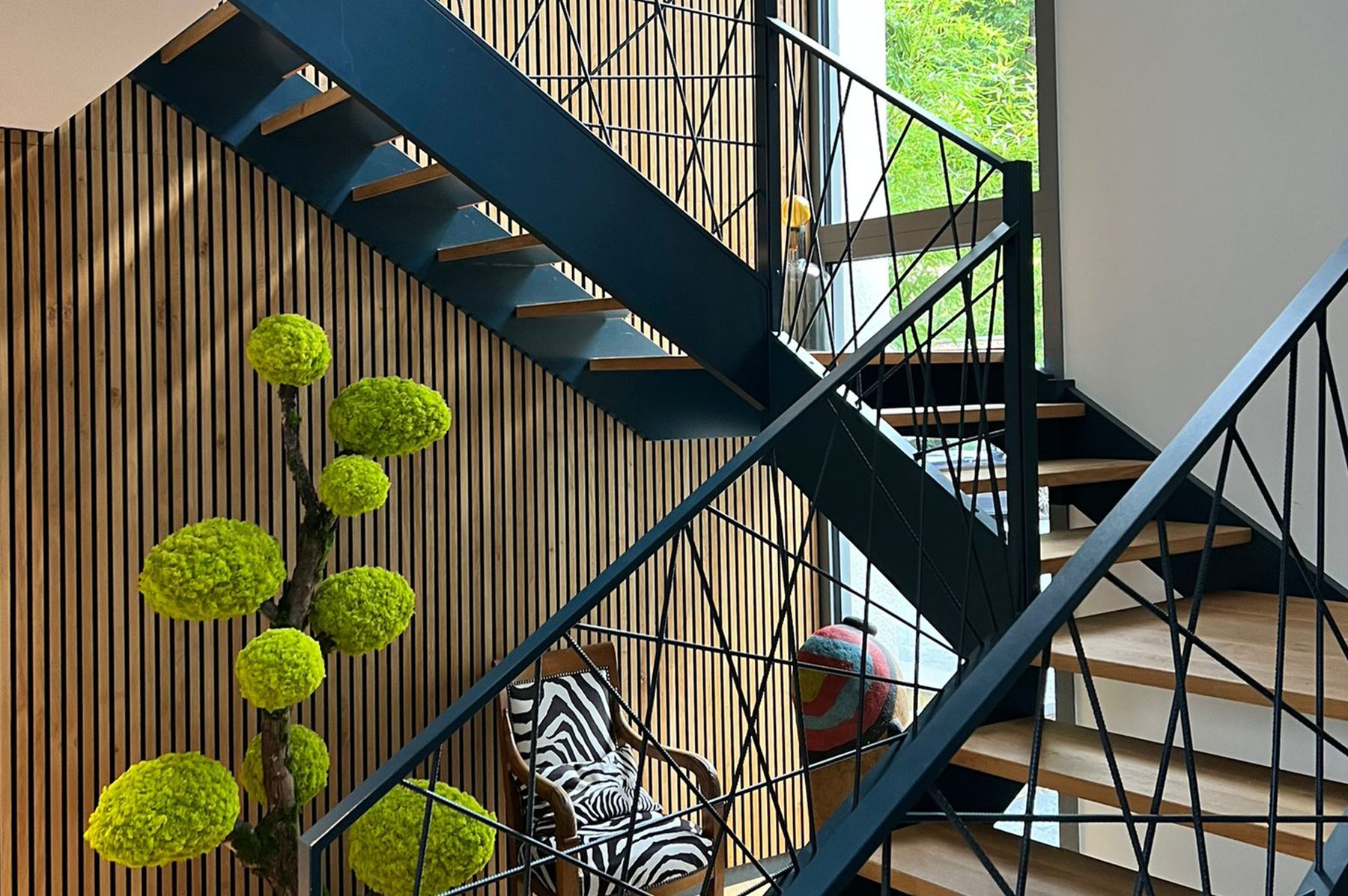 Escalier aux garde-corps noirs et marches en chêne