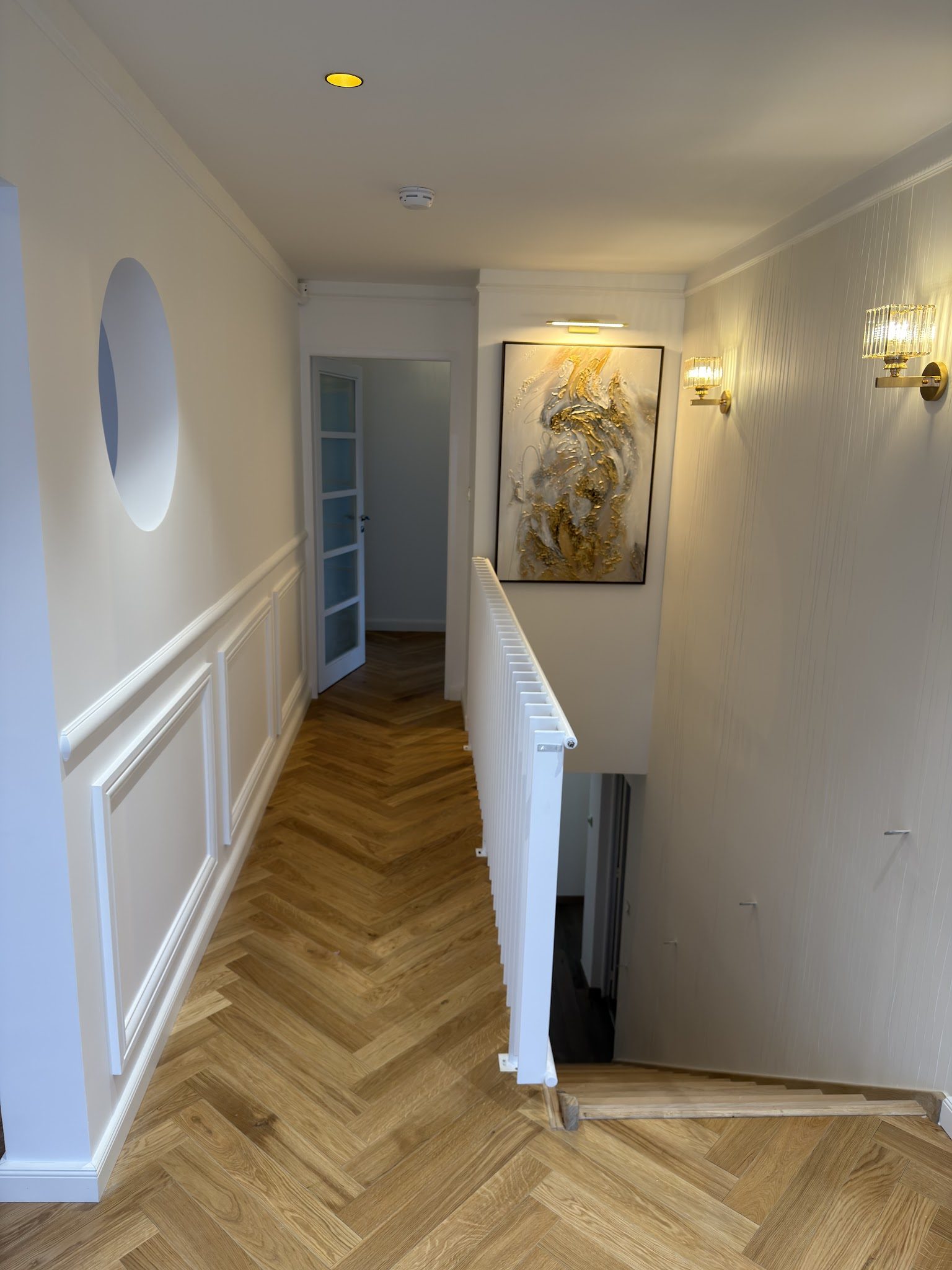 Couloir blanc à moulures et lampes dorées