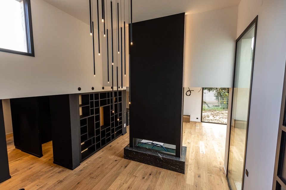 Pièce à vivre aux volumes noirs et parquet clair